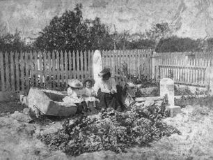 a woman and several children sit on a grave
