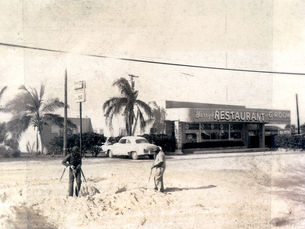 Two people in front of a building labeled Harry's Restaurant