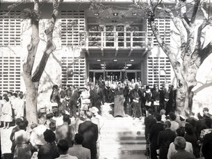 A group of people facing a line of other people around a person at a lectern.