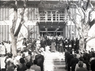 A group of people facing a line of other people around a person at a lectern.