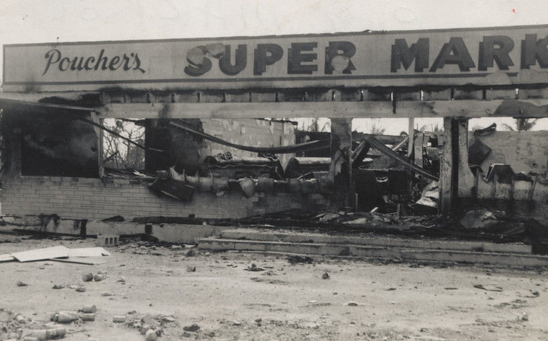 A burned shell of a building with a sign that reads Poucher's Super Market
