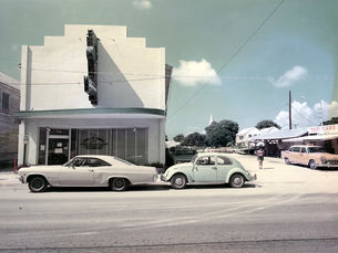 Two cars in front of a building with an awning and a marquee sign.