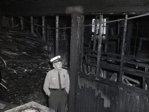 A man in a fire department uniform inside a burned out structure