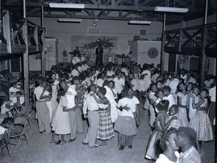 A room full of people dancing while a band plays on a stage.