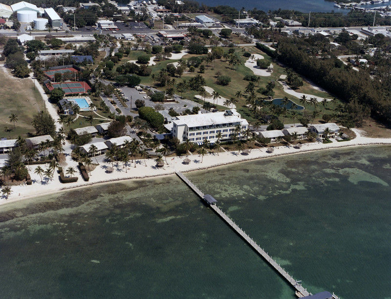 Aerial view of a shoreline with a large building and a long pier.