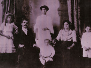 Two adults and a child seated and three children standing