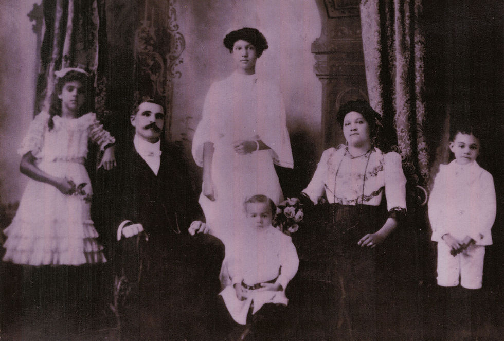 A family with two adults and a child seated and three children standing