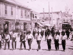 Police officers marching in a parade with a streetcar behind them.