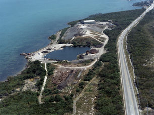 Aerial view of a shoreline with a highway and a landfill.