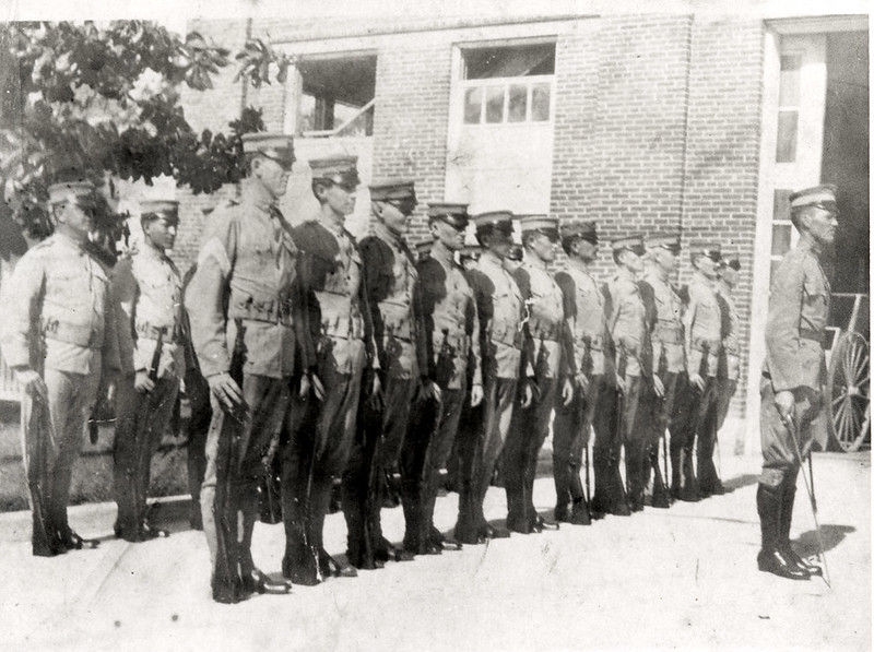 Rows at marines outside in front of a brick building.