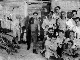 A group of men outside a wooden building.