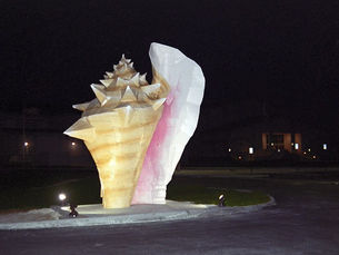 a large sculpture of a conch shell illuminated by floodlights