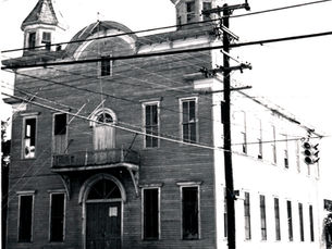 A two story building with a balcony on the second floor and two turrets at the corners.
