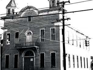 A two story building with a balcony on the second floor and two turrets at the corners.