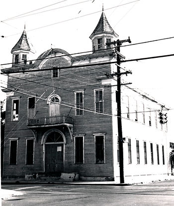A two story building with a balcony on the second floor and two turrets at the corners.