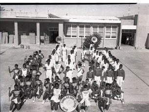 A high school band lined up behind a bass drum labeled Douglass High School Band.