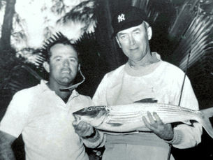 Two men with the man on the right holding a fish