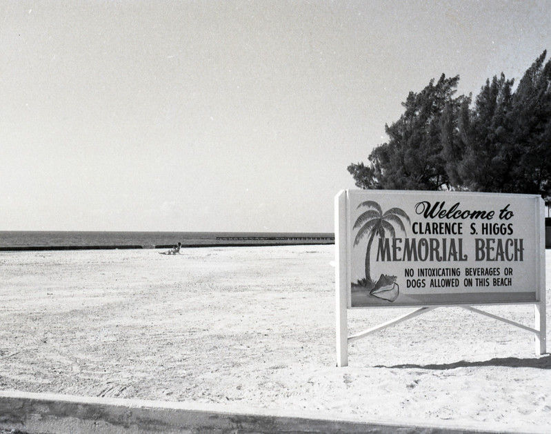 A beach with a sign that reads Welcome to Clarence S. Higgs Memorial Beach. No intoxicating beverages or dogs allowed on this beach.
