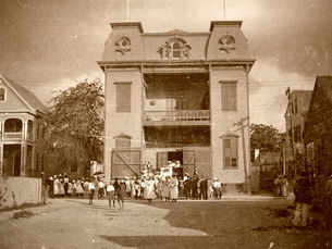 A group of people in front of a three-story building.