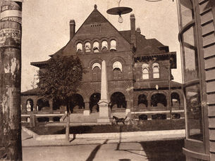 a three story brick building with a monument in front of it.