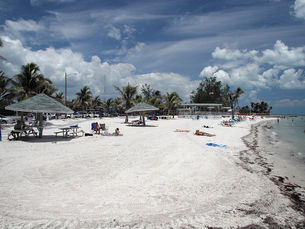 A beach with several shelters and people lying on the sand