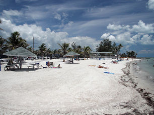 A beach with several shelters and people lying on the sand