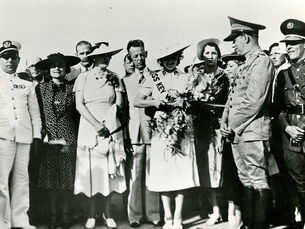 A group of people watch as a woman wearing a sash that reads Miss Key West cuts a ribbon
