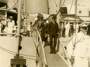 People walking down a gangplank from a Navy ship