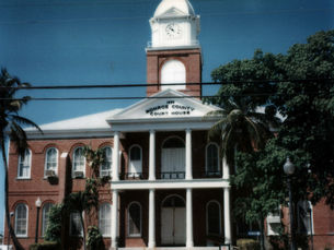 a two story brick building with a clock tower in the center and a sign reading Monroe County Court House on the facade.
