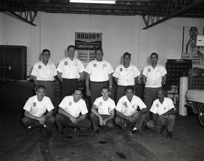 Five men kneeling and five men standing in a garage.