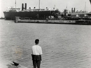 A person looking across water at a ferry on a pier