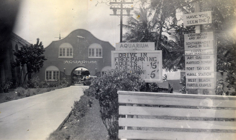 A building in the background with Aquarium written over the arched doorway with signs in front.