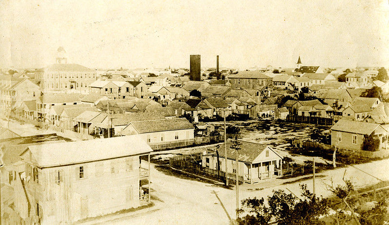 Aerial view of a town with streets and buildings, mostly one- and two-story.