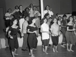 A group of people on a dance floor and musicians on a stage behind them.