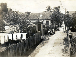 A dirt lane surrounded by houses and fences and a line with laundry