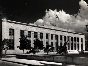 A large two-story stone building with signs on the front reading Post Office, Custom House and Court House.