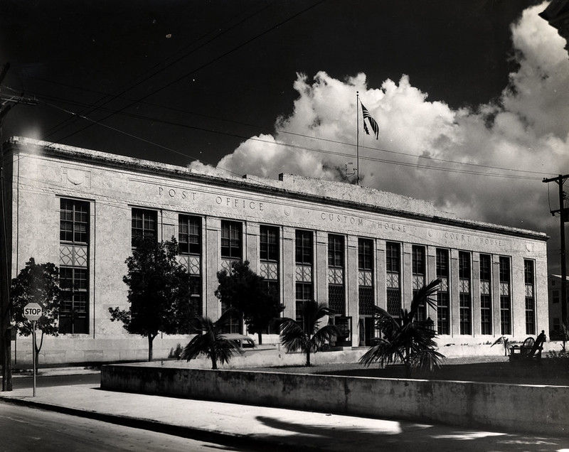 A large two-story building with signs on the front reading Post Office, Custom House, Court House.