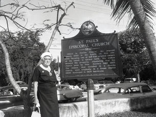 A woman standing next to a historical marker for St. Paul's Episcopal Church.