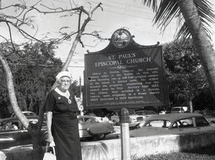 A woman standing next to a historical marker for St. Paul's Episcopal Church.