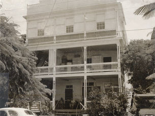 a three story wood frame house with porches on the first two floors.