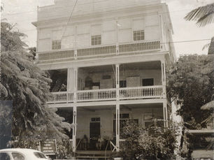 a three story wood frame house with porches on the first two floors.