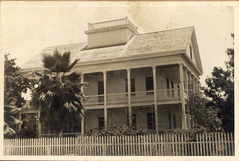 A wooden house with porches on the first and second floors.