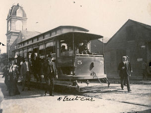 A streetcar with people on and around it. Writing on the photo reads streetcar and 1904.