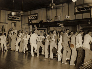 a line of men and one woman standing in front of a bar