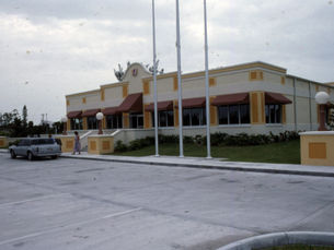 a building with a conch shell in the facade and three flagpoles in front