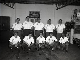 Five men kneeling and five men standing in a garage.