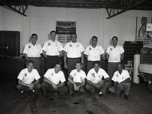 Five men kneeling and five men standing in a garage.
