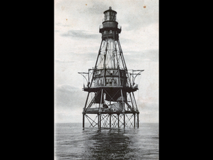 a lighthouse on the water with an enclosed structure halfway up