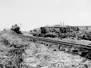 A locomotive on and wreckage next to train tracks