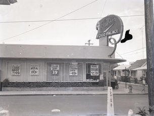 A grocery store with signs offering prices in the window and a sign that reads Fausto's Food Palace.